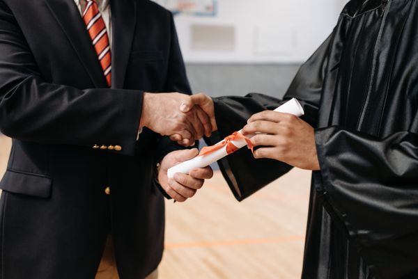 Gros plan sur un diplômé recevant son diplôme lors d'une poignée de main durant la cérémonie de remise des diplômes.