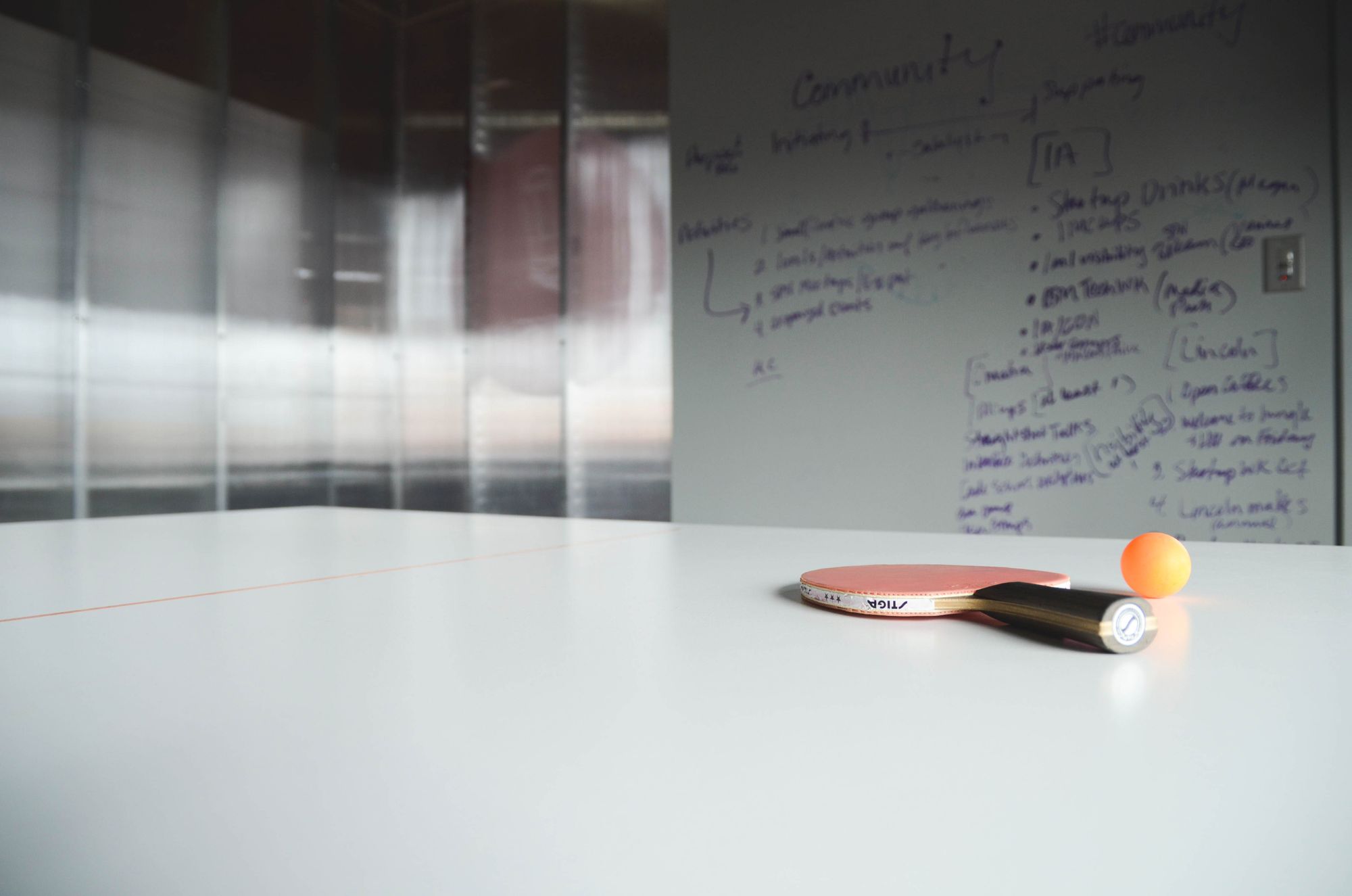 Gros plan sur une raquette et une balle de ping-pong sur un bureau ; espace de travail créatif.