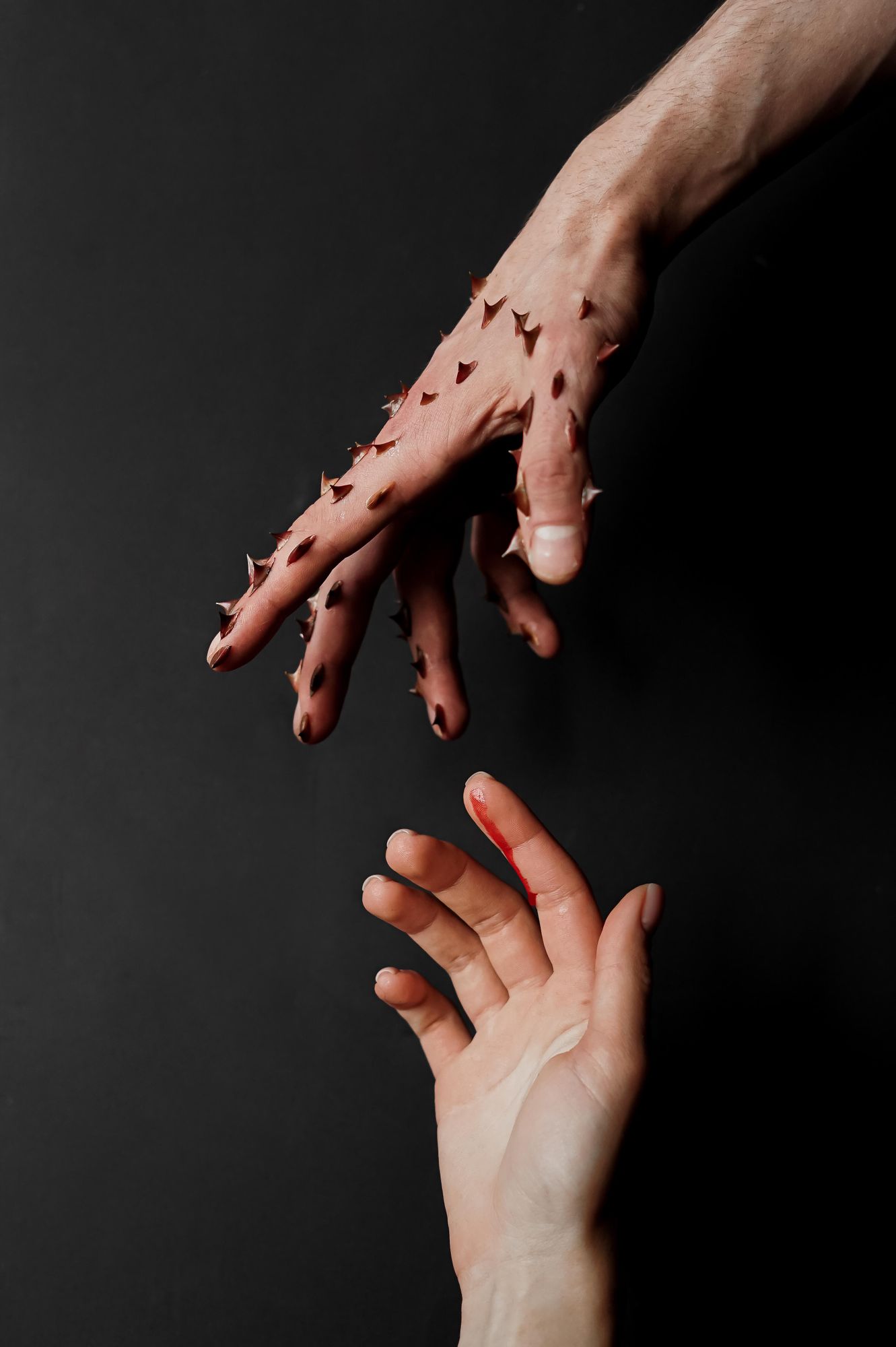 Image saisissante de deux mains humaines sur fond noir ; l'une est couverte d'épines.