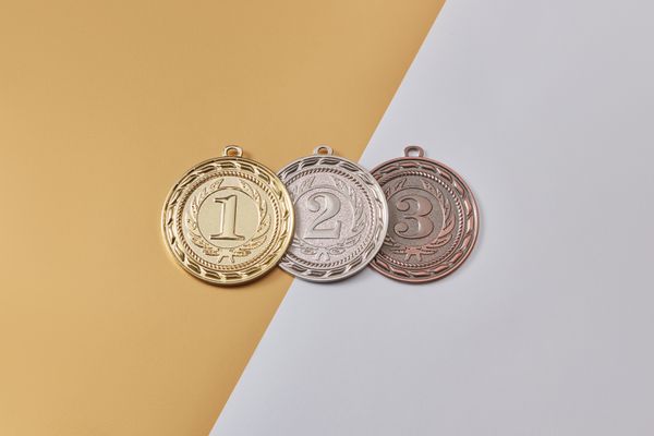 Médailles d'or, d'argent et de bronze disposées sur un fond moderne bicolore, symbolisant la réussite.